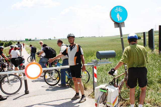 Ein Radfahrer zeigt verärgert auf einen der Schranken.