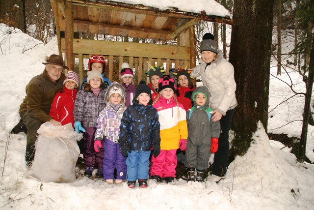 Karl Binder und die KIndergärtnerin Brigitte Rieder mit einer der Kindergruppen vor einer Futterkrippe.