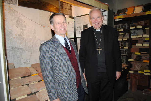 Bezirksmuseums-Mitarbeiter Peter Singer erklärt Kardinal Christoph Schönborn die spezifischen Signaturen, die auf den ausgestellten alten Ziegelsteinen zu sehen sind.