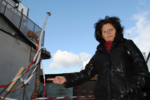 Anrainerin Silvia Heck zeigt auf die freigelegten Leitungen und Kabeln – Überreste eines abgerissenen Standls am Victor-Adler-Markt.