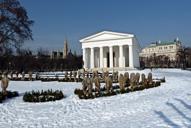 Theseustempel im Volksgarten, flankiert von Rathaus (li) und Burgtheater (re), als Bildvordergrund dienen winterlich verpackte Rosenstöcke