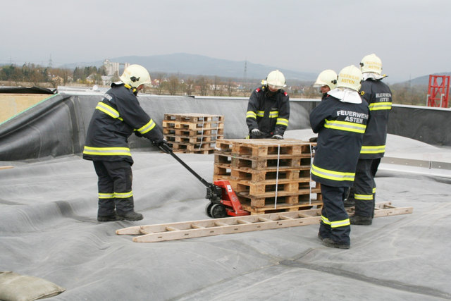 Mit Euro-Paletten und Sandsäcken versuchten die Einsatzkräfte die losgelöste Dachfolie zu beschweren.