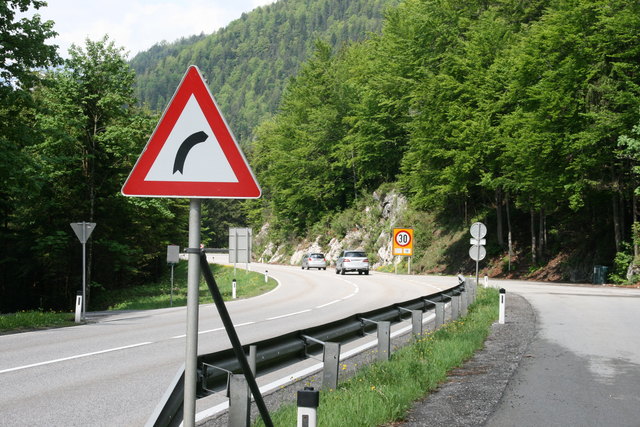 Die Beschilderung weist auf den für eine Hauptstraße ungewöhnlichen Kurvenradius hin. Bald wird die Kurve begradet.
