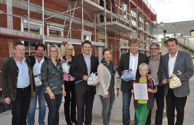 Gemeinsam stoßen Bauherrn, Baumeister und die neuen Mieter auf das neue Gebäude an