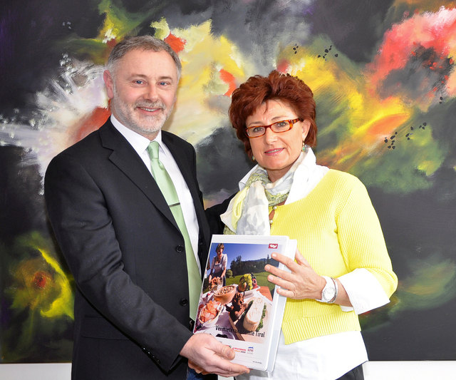 Gerhard Föger, Leiter der Abteilung Tourismus des Landes Tirol, übergibt die Mappe der Vermieterakademie Tirol an die Vermieterin Notburga Haider aus Gries im Sellrain.