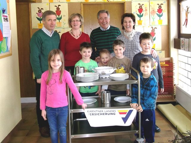 Im Bild v.li.: Übergabe des Servierwagens von der KLV an den Kindergarten, BL Johann Polessnig, Anni Koschier, Bgm. Anton Polessnig und Leiterin Sonja Klatzer mit einer Gruppe der Kindergartenkinder.