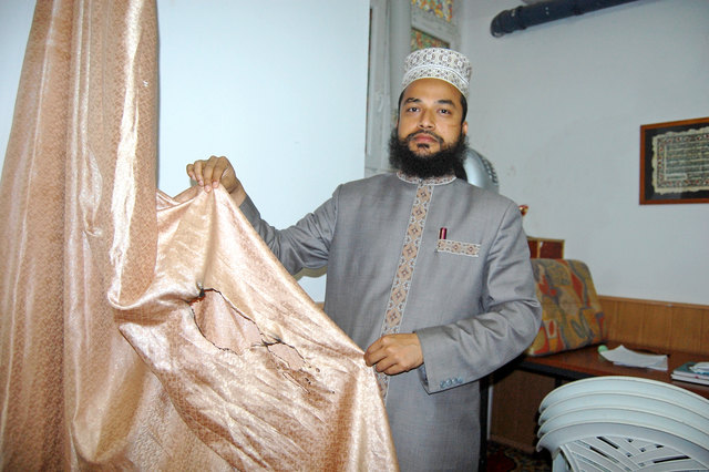 Der Imam Muhammad Abdul Quaiyum zeigt einen der Vorhänge, der in Brand gesetzt wurde.