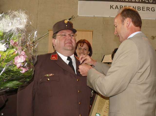 Bezirkshauptmann Rüdiger Taus überreicht das silberne Ehrenzeichen der Gemeinde Miesenbach an Kommandanten Gerald Arbesleitner.