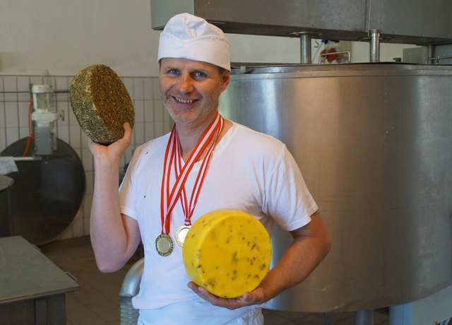 Käser Georg Wimmer mit seinem prämierten Rohmilchtilsiter mit Kräutermantel und einem Jalapeno-Chili-Käse.