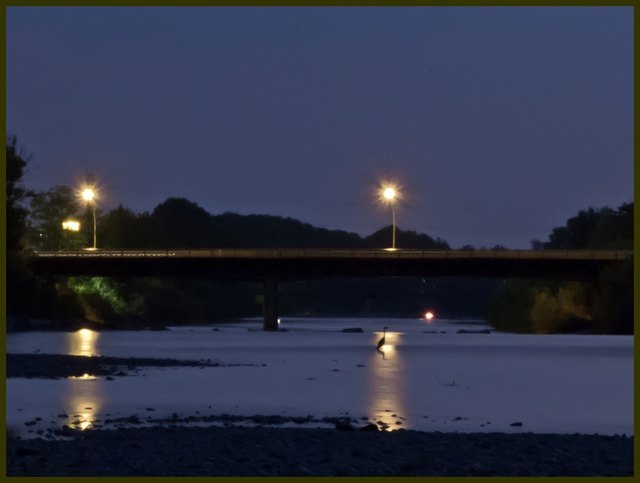 Brücke über der Ache und im Lichterschein ein Kranich