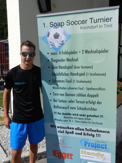 Christopher Trutschnig vor dem offiziellen Plakat vom 1. Soap Soccer Turnier in Kirchdorf in Tirol.