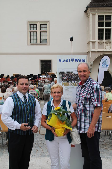 Organisator Wolfgang Homar überreichten der 5.000sten Besucherin der diesjährigen Burggartenkonzerte einen Blumenstrauß, stellvertretend für alle treuen Besucher der Sommerkonzerte im Welser Burggarten. V.l.n.r.: Herr und Frau Zehtner aus Thalheim.