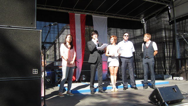 Mag. Tsuyoshi Kawakara, Leiter des Japanischen Informations- und Kulturzentrums, der Kulturabteilung der Japanischen Botschaft in Wien, welche wieder den Ehrenschutz über die Veranstaltung übernommen hatte, bei seiner Eröffnungsrede. Links eine Vertreterin aus dem Management des Hauptsponsors der Veranstaltung, JTI/AT, rechts Moderatorin Astrid Nowak, Bezirksvorsteher Franz Prokop und August Nowak, Vorstandsvorsitzender des Veranstalters Bildungsagentur und Ottakring 16+.