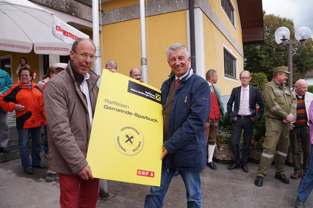 Herbert Thiem, der Geschäftsleiter der Raiffeisenkasse Hallwang und Mayrwies, übergibt das 500 Euro Gemeinde-Sparbuch an den Hallwanger Ortschef Helmut Mödlhammer.