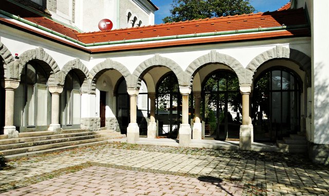 Die Kirche ist durch Arkaden mit dem östlich gelegenen Pfarrhof verbunden, der Merkmale des Heimatstils aufweist.