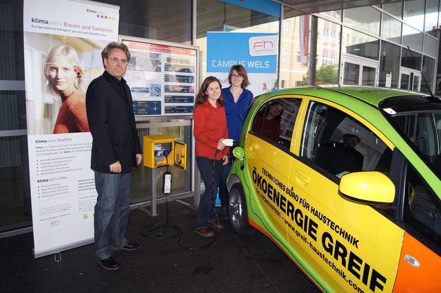 Herbert C. Leindecker mit den wissenschaftlichen Mitarbeiterinnen Susanne Luger und Isabella Dornigg vor der Photovoltaik-Anzeigetafel und Solartankstelle der FH OÖ Fakultät für Technik und Umweltwissenschaften in Wels.