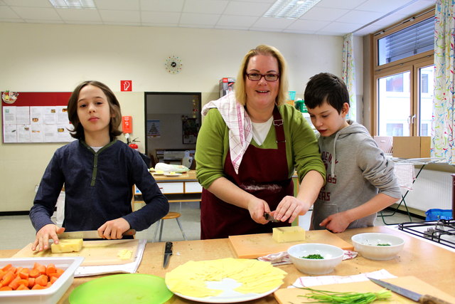 Gesundes Essen für alle: Martin (li.) und Eyüp (re.) helfen Klassenvorstand Karin Beranek beim Zubereiten der Jause