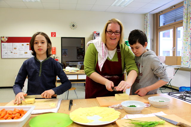 Gesundes Essen für alle: Martin (li.) und Eyüp (re.) helfen Klassenvorstand Karin Beranek beim Zubereiten der Jause