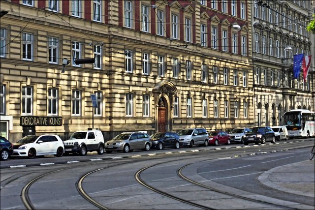 Die Abendsonne, die sich in der Glasfront des Bahnhofsgebäudes spiegelt, wirft helle Reflexe auf die gegenüberliegende Hausreihe