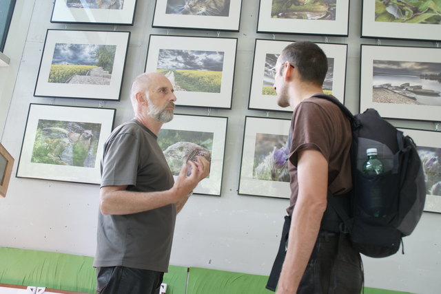 Wolfgang Dolak mit einem Vernissage-Besucher, er erklärt Fotografie-Techniken.