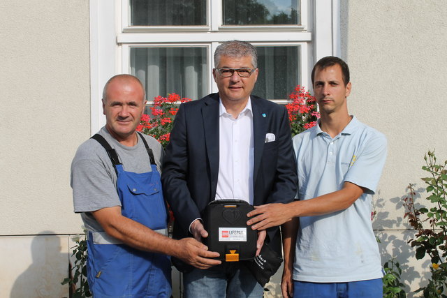 Bürgermeister Kurt Burghardt mit einem Defibrillator und den Bauhofmitarbeitern, die ihn im Foyer des Rathauses Gänserndorf montiert haben. | Foto: privat