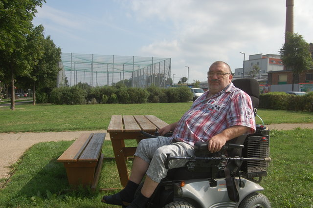 Franz Kölsch vor dem Tisch, an dem bei Schönwetter die Jugendlichen feiern. Im Hintergrund der Fußballkäfig.