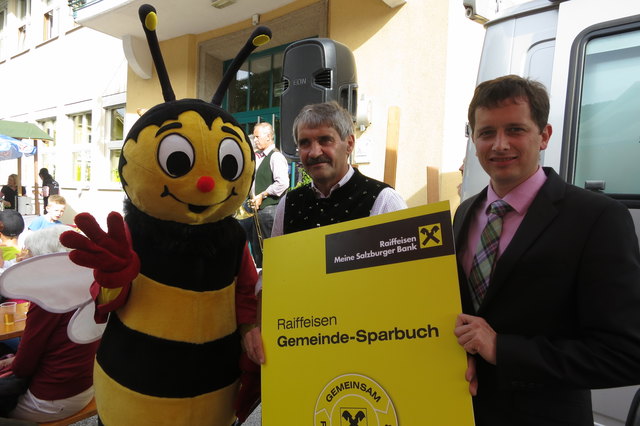 Raiffeisen-GF Andreas Quehenberger (re) übergibt mit Sumsi das Gemeinde-Sparbuch an Bgm Sepp Schwarzenbacher. | Foto: Foto: Isabell Gunzer, ORF Radio Salzburg