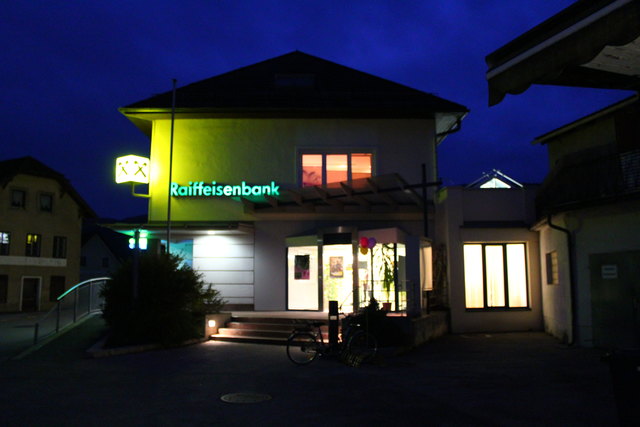 Ein nicht alltägliches Bild: die Raiffeisenbank hell erleuchtet in der Dämmerung.