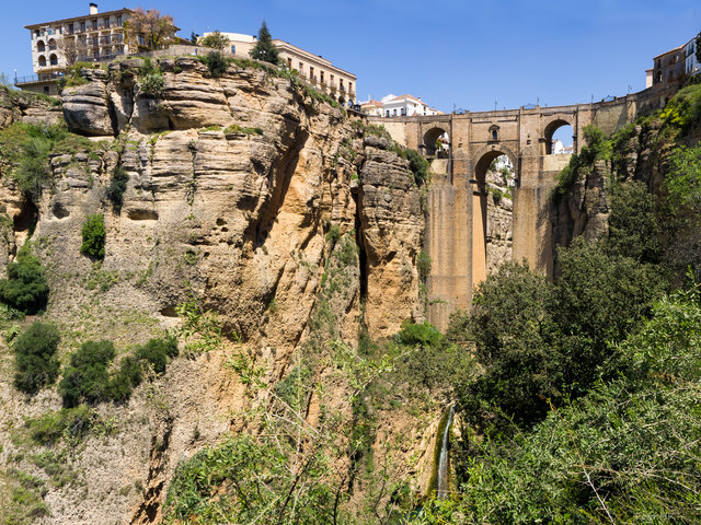 Die Straßenbrücke überspannt den Río Guadalevín, der in der ca. 120 Meter tiefen Schlucht El Tajo fließt. Panorama aus 4 Hochformatbildern.