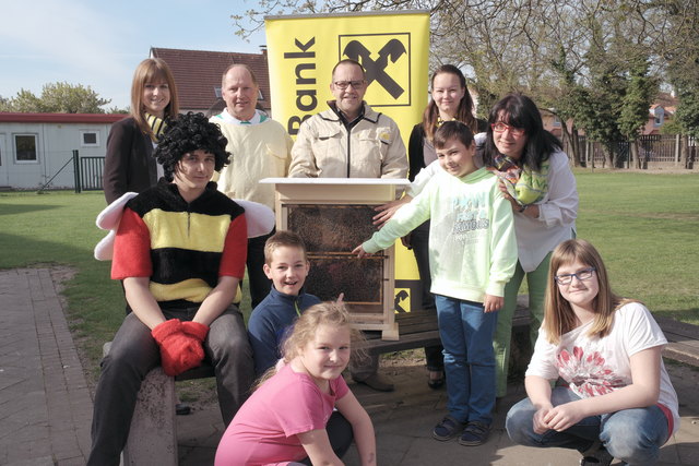 Projektvorstellung: Gemeinderat Benedikt Wallner (als Riesenbrummer), der Schaubienenstock und die Initiatoren mit den Raiba-Ladys Sandra Gersthofer und Claudia Hainfellner im Kreis der Schüler.
