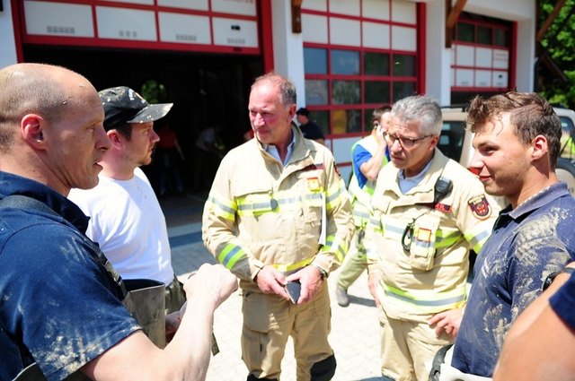 Lds.-Kdt. LBD Ing. Peter Hölzl und Bez.-Kdt. Reinhard Kircher im Gespräch mit Feuerwehrmännern, die sich vom anstrengenden Arbeitseinsatz erholen.
