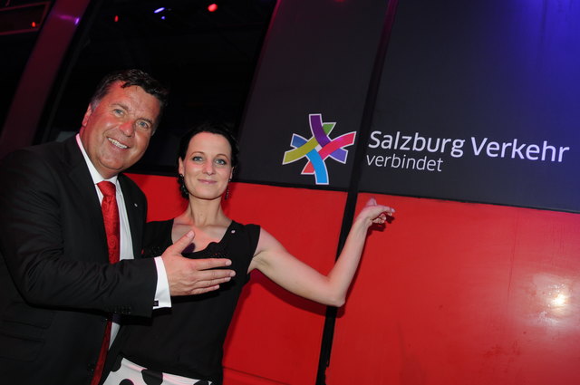 SVV-Geschäftsführerin Allegra Frommer mit LR Hans Mayr vor dem neuen Logo des Salzburger Verkehrsverbundes