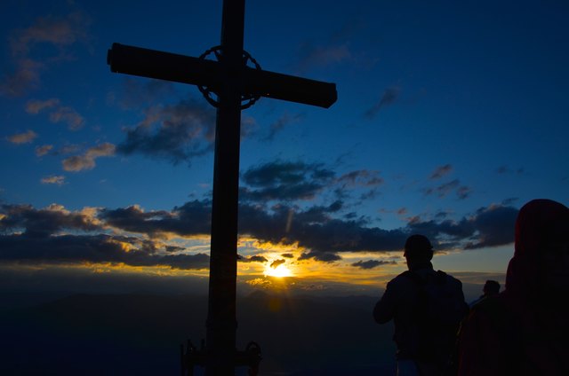 Silhouetten und Gipfelkreuz bei Sonnenaufgang am Goldeck.
