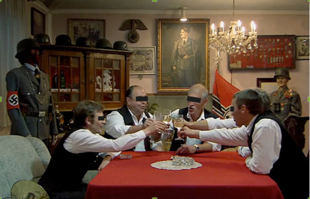 Screenshot aus dem Trailer zu "Im Keller" mit den Ex-Gemeinderäten unter Hitler-Bild und Hakenkreuzfahnen.