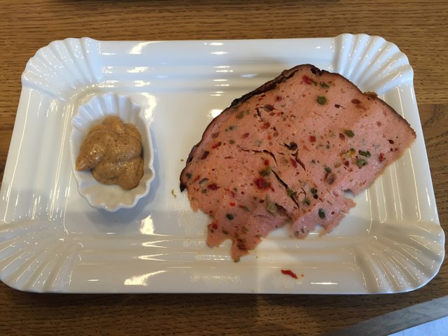 Chili-Leberkäse: Beim ersten Bissen schmeckt man noch die Schärfe der Zutaten, aber danach schmeckt er exzellent und würzig.  Empfehlenswert dazu: ein Stück Brot oder Gebäck.