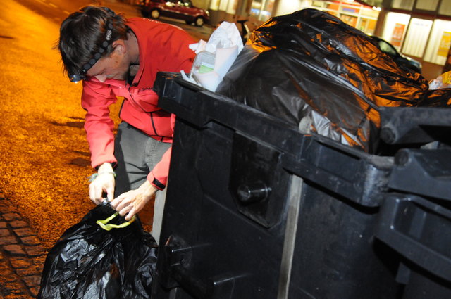 Waste-Diver Lukas Uitz hält Ausschau nach genießbaren Lebensmitteln in der Mülltonne eines Supermarktes.