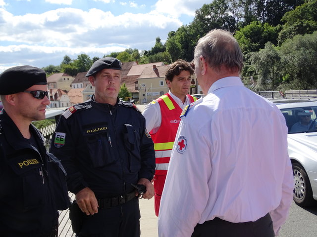 Polizei und Rotes Kreuz bei der Besprechung vor dem Eintreffen der dritten Menschengruppe.
