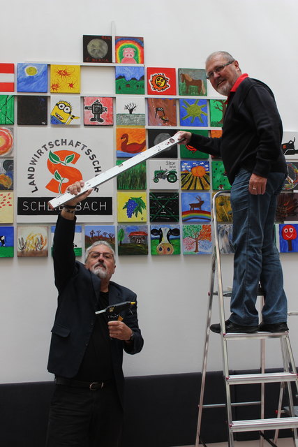 Kurt Schiffel mit Fl. Josef Preundler beim Anbringen der Bilder an der Wand.