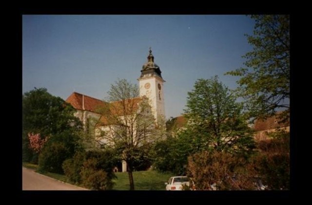 Beginn des Schulgeländes. Blick zum Lehrerparkplatz, zum Fahrraddach und zur Stadtpfarrkirche. Aufnahme aus dem Frühjahr