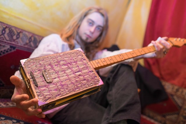 Instrumentenbauer Raffael Lenz zeigt eine seiner selbstgebauten Cigar-Box-Gitarren.