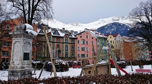 Links die Geographensäule beim Spielplatz, dahinter die Häuserzeile an der Innstraße und die schneebedeckte Nordkette. Aufgenommen am 24.01.2016 um 11:32 Uhr.