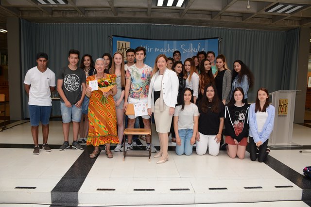 Elisabeth Cerwenka und Direktorin Sigrid Steiner mit einem symbolischen Sessel und einigen Schülern. | Foto: HAK Wörgl