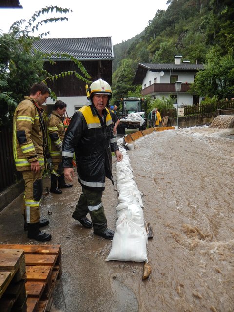 Der Möserer Bach in Pettnau bedroht die darunterliegenden Häuser. Die Feuerwehr Pettnau versucht die Wassermassen umzuleiten. | Foto: zeitungsfoto.at