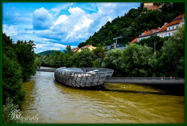 Die „Insel“ liegt flussaufwärts des Edegger-Stegs, also wenig nördlich der Hauptbrücke, zwischen dem Schlossberg und dem Kunsthaus. Sie ist von beiden Murufern über einen Steg erreichbar.