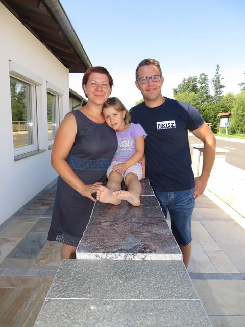 Karina, Susanne und Alexander Fikisz an einer Mustersteinmauer.