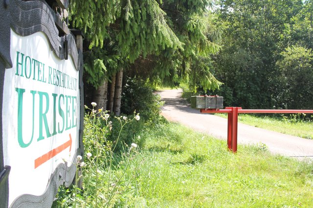 Ein Schild weist am Parkplatz bei der B179 auf das Hotel hin. Ein Schranken verwehrt noch die Zufahrt.