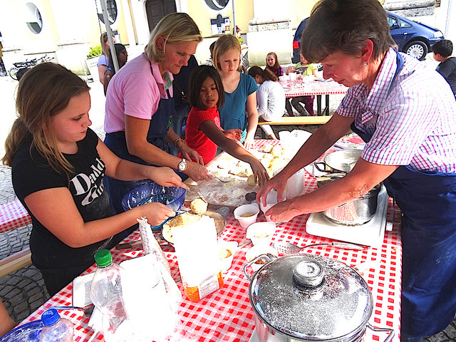 Die Bäuerinnen bereiten mit den Kindern Zwetschgenknödel zu.