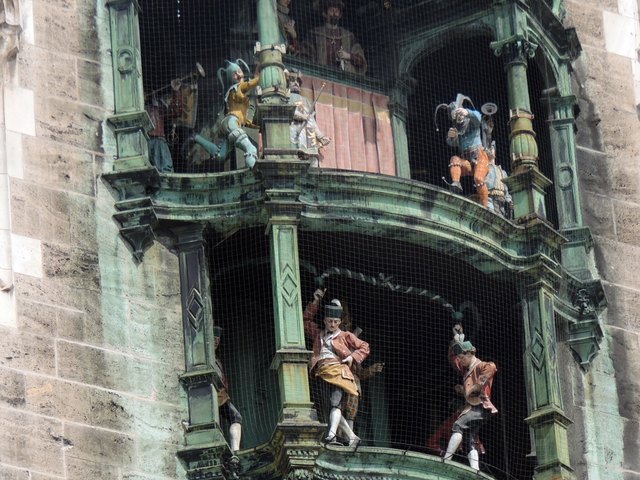 der Blick zum Glockenspiel, beim Rathaus von München. wo um 11 u 12 Uhr 43 Glocken ertönen. Ersichtlich ist der Spielerker der hat 32 Spielfiguren sie beziehen sich auf Motive der Geschichte u Sagen von München.Im oberen Teil ist ein Turnier dargestellt das zur Vermählung von Herzog Wilhelm V mit Renata von Lothringen abgehalten wurde.
