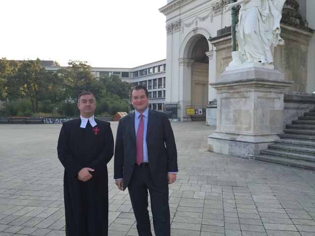 Pfarrer Martin Pastrnak mit Johannes Pasquali vor dem Winterthurgebäude. Derzeit ist das Bürogebäude niedrig und dezent hinter Bäumen verborgen.