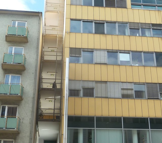 Etwas vergrößert die hell erleuchteten fünf unteren Raucherbalkone auf der Rückseite des Stadtbauamtes während der hellen Tageszeit.